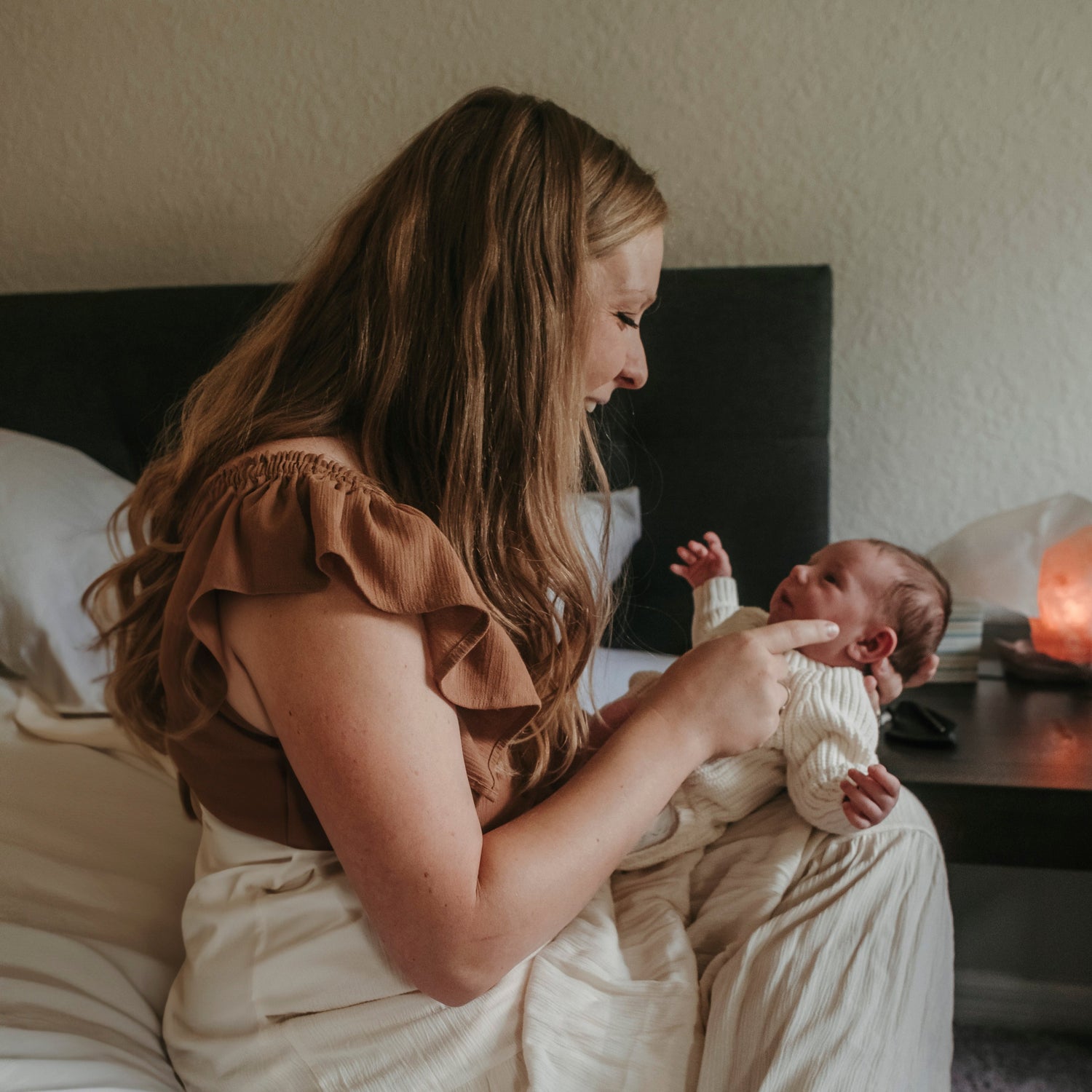 postpartum mother holding newborn baby smiling gazing into each other's eyes
